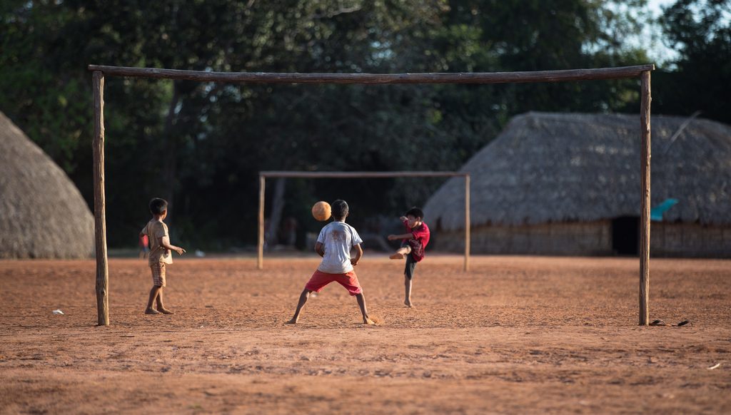 Children playing football. Photo taken during the celebration of the 10th anniversary of the Yarang Women's Movement (MMY). MMY produces and collects native seeds for reforestation of springs and riparian forests in the Xingu River basin around TIX, Aldeia Moygu, Mato Grosso @Carol Quintanilha / ISA