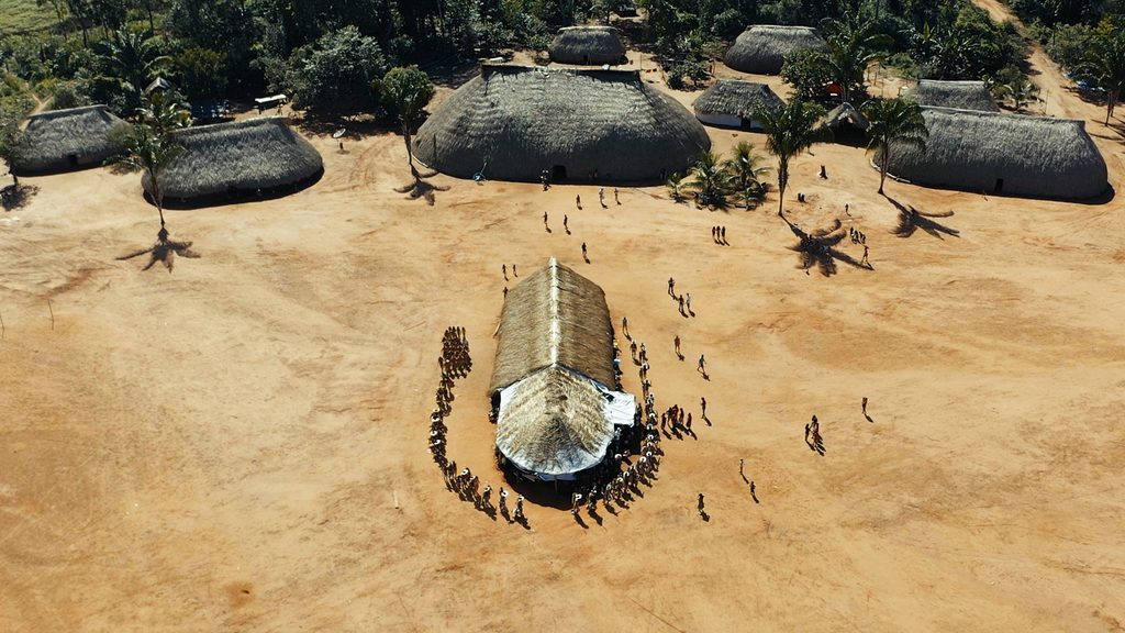 Aerial view of the village in celebration, Aldeia Moygu, Xingu Indigenous Park. Scene from the movie "They will never walk alone", in celebration of the 10th anniversary of the Yarang Women's Movement (MMY), which produces and collects native seeds for the reforestation of springs and riparian forests in the Xingu River basin around the TIX. Directed by Fernanda Ligabue/ISA and carried out by the Yarang Women's Movement, Xingu Seeds Network Association and Moygu Indigenous Association Ikpeng Community @file:///home/alex/Desktop/Xingu