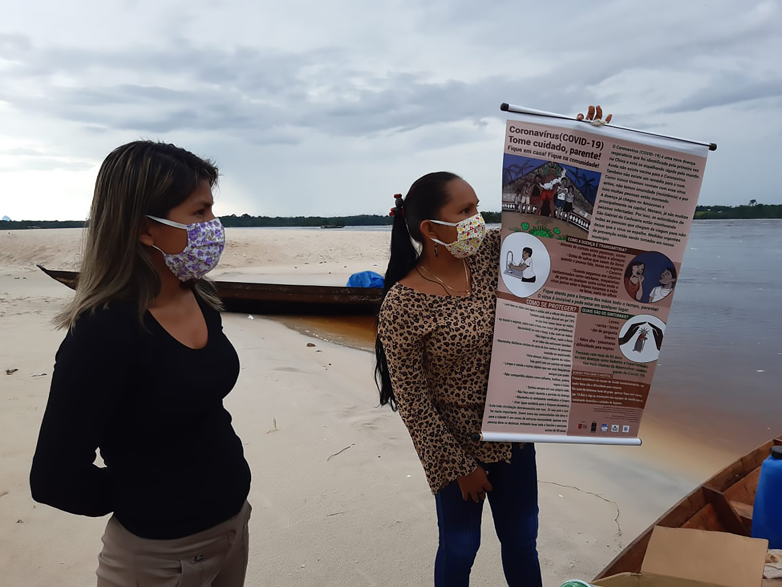 Adelina Desana (à esquerda) e Elizângela Baré (à direita), levam banner de prevenção para a comunidade do Waruá, do povo Dâw, em abril de 2020|Rede Wayuri