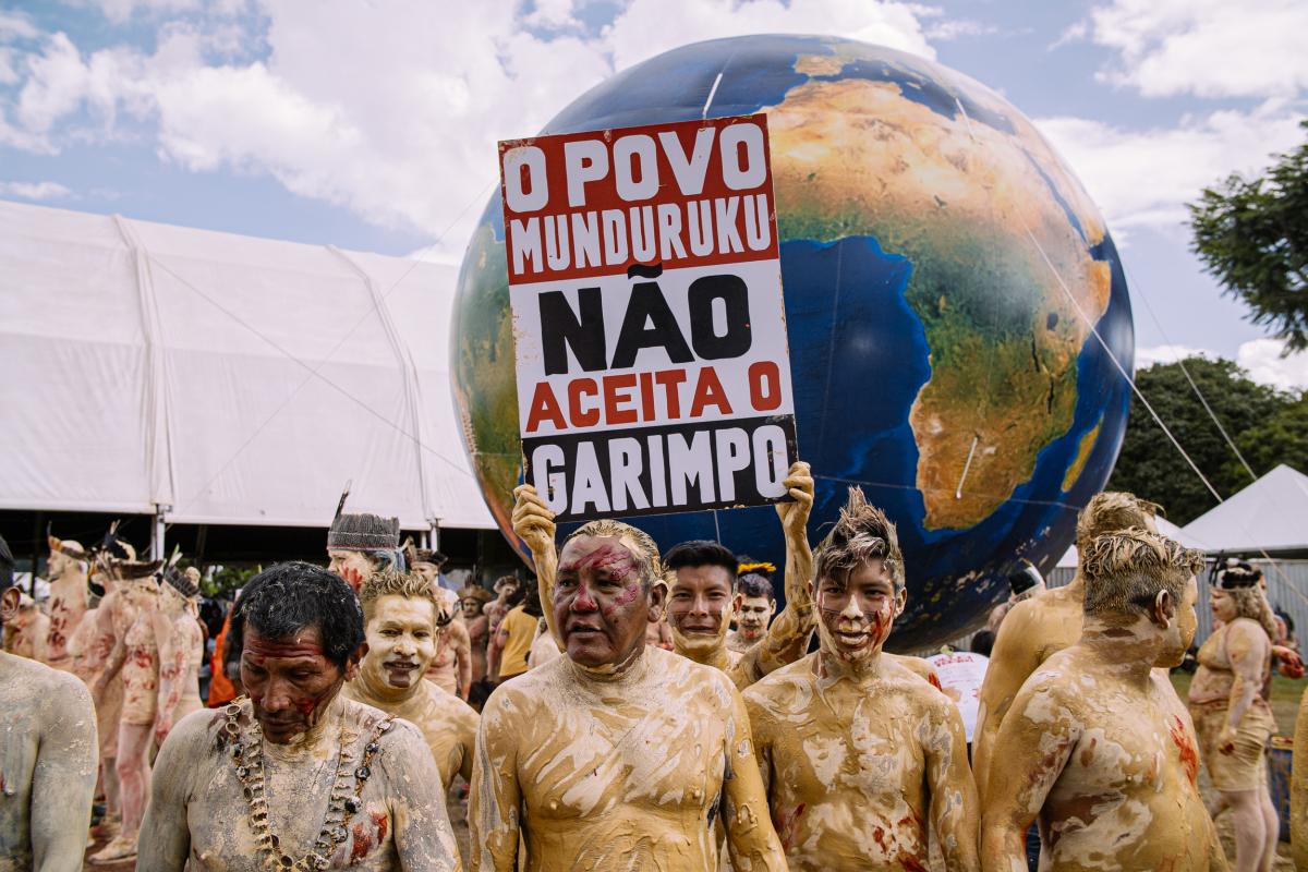 Homem segura placa ¨O povo munduruku não aceita garimpo" durante Protesto Contra Garimpo Ilegal em Terras Indígenas, em Brasília.