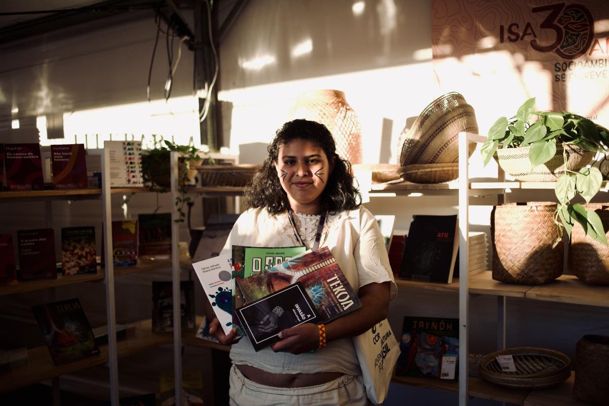 Kerexu Mirim folheia livros sobre seu povo e família na tenda do ISA n'A Feira do Livro, que acontece em São Paulo