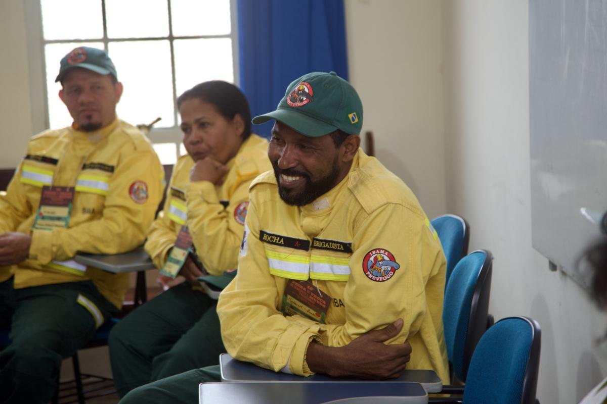 Brigadista do Prevfogo sorri sentado em mesa de conversa sobre manejo do fogo