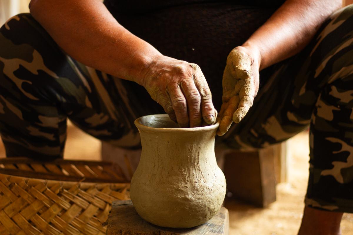 Imagem mostra uma pessoa moldando um vaso de cerâmica