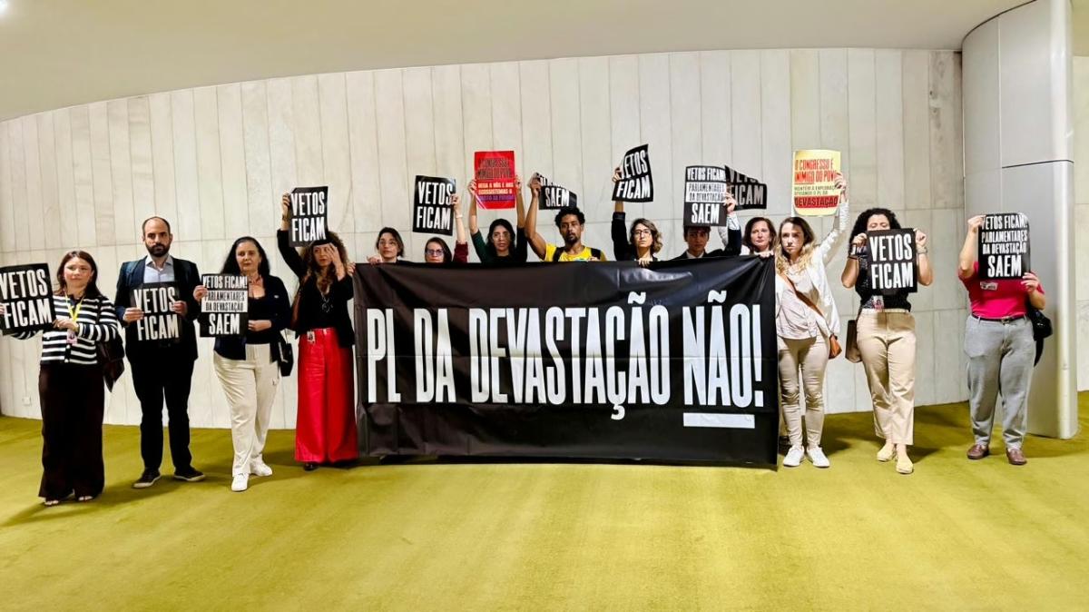 Imagem mostra pessoas segurando uma faixa preta onde é possível ler em letras garrafais brancas "PL da devastação não!"
